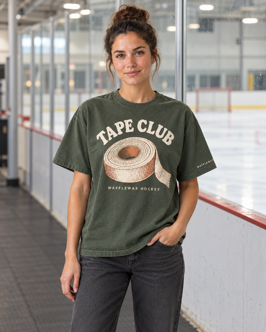 AI-generated lifestyle mockup of a woman wearing the moss green Tape Club tee beside an ice rink.